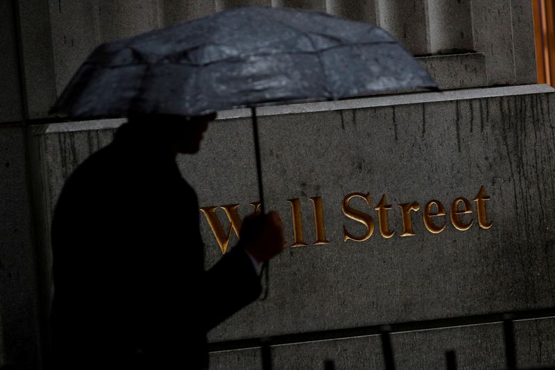 © Reuters. FILE PHOTO: A man walks through the rain on Wall St. outside the NYSE in New York