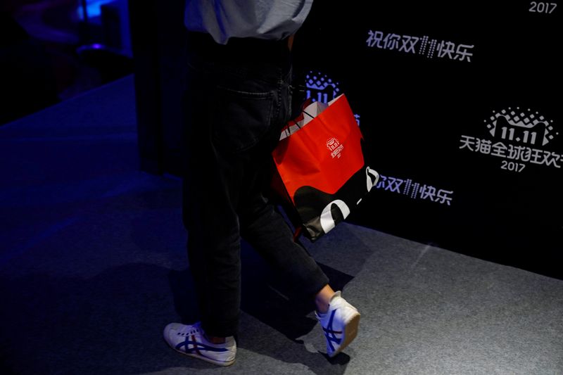 © Reuters. FILE PHOTO: A woman walks with a shopping bag during Alibaba Group's 11.11 Singles' Day global shopping festival in Shanghai