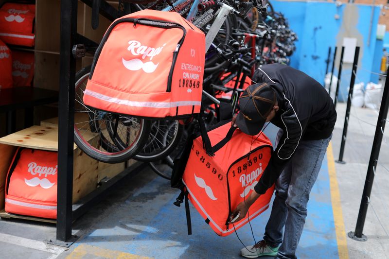 © Reuters. FILE PHOTO: A Rappi delivery man picks up his delivery bag, from his bicycle, in Bogota