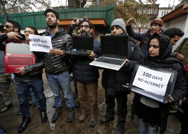 © Reuters. FILE PHOTO: Kashmiri journalists display laptops and placards during a protest demanding restoration of internet service, in Srinagar