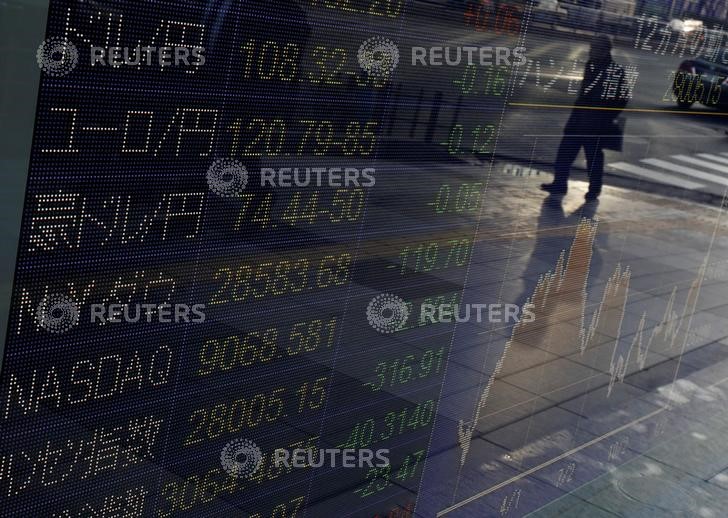 © Reuters. Un hombre se refleja en una pantalla electrónica que muestra los índices de los mercados mundiales y los tipos de cambio del yen japonés frente a las monedas mundiales fuera de una correduría en Tokio