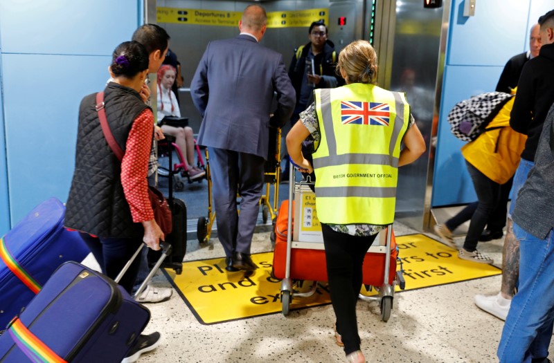© Reuters. FILE PHOTO: An official assists passengers at Manchester Airport, Britain