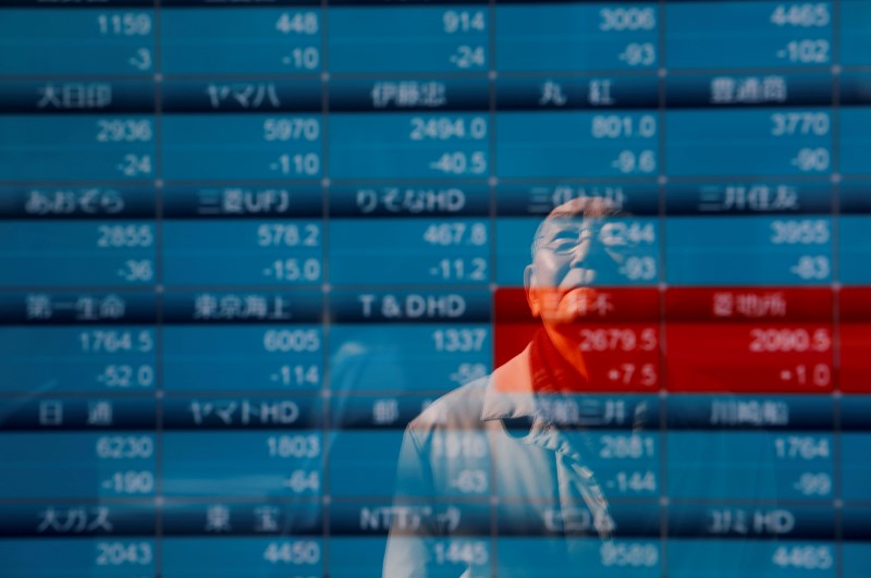 © Reuters. A man is reflected on a board showing stock prices outside a brokerage in Tokyo