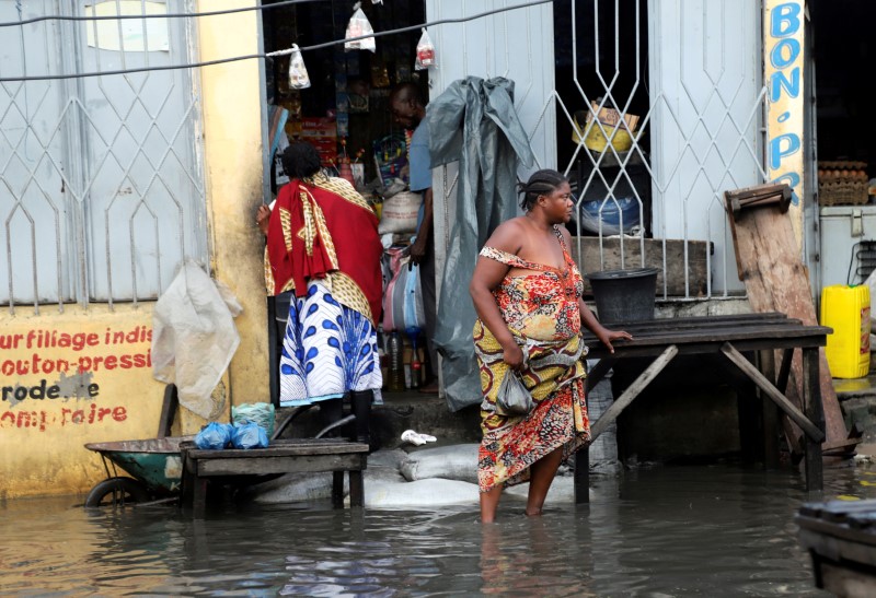 © Reuters. FILE PHOTO: A Congolese woman walks from a shop through floodwaters along a street after the Congo River burst its banks due to heavy rainfall in Kinshasa