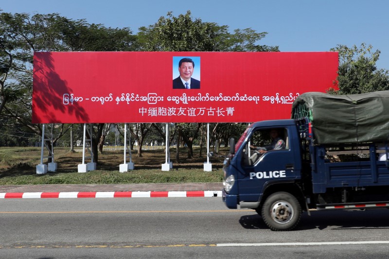 © Reuters. A police van drives by a banner welcoming Chinese President Xi Jinping ahead of his visit to Myanmar in Naypyitaw