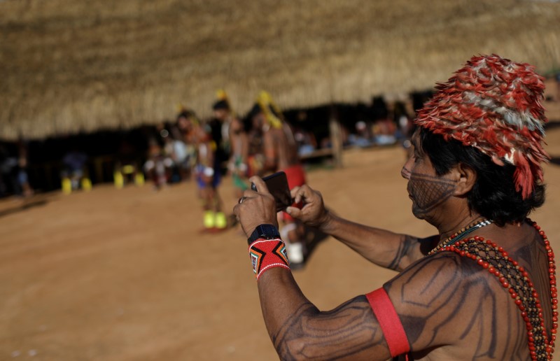 © Reuters. An indigenous man films a performance during a four-day pow wow in Piaracu village near Sao Jose do Xingu