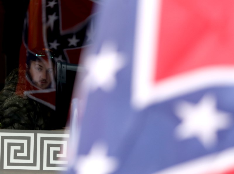 © Reuters. A man watches from a diner as supporters of the continued display of Confederate generals’ statues and other symbols march with Confederate flags in Lexington, Virginia