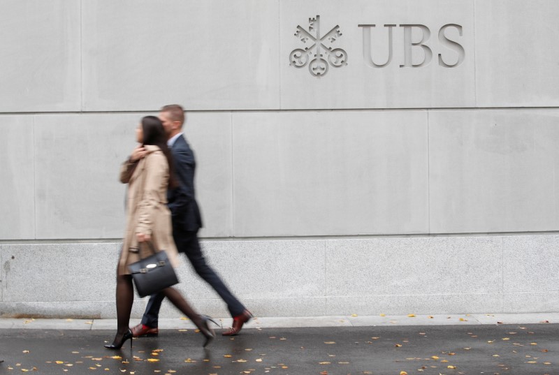 © Reuters. FILE PHOTO: People walk past a logo of Swiss bank UBS in Zurich