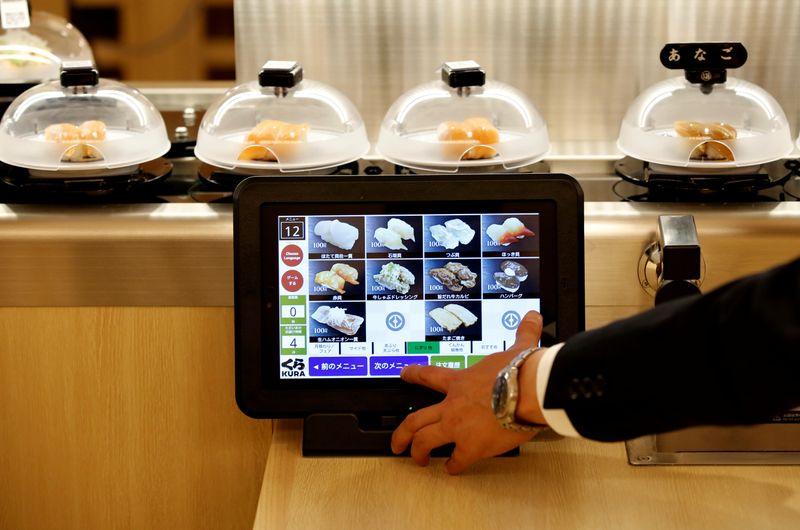 © Reuters. A man orders sushi through a touch screen device during a media event a day before the official opening of Kura Sushi's new branch in Tokyo