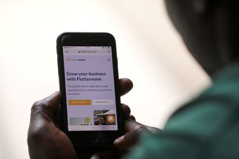 © Reuters. Man poses as he displays Flutterwave homepage on mobile phone screen in Abuja