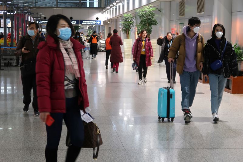 © Reuters. Passengers wearing masks are seen at the terminal hall of the Beijing Capital International Airport, in Beijing