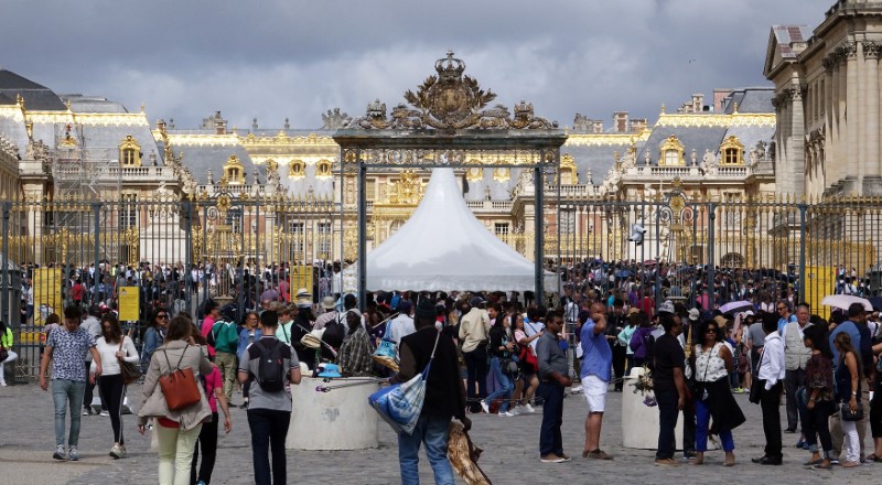 © Reuters. FILE PHOTO: Tourists stand in queue at the entrance to the Chateau de Versailles