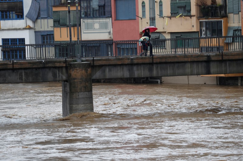 © Reuters. Residents walk on a bridge on the Onyar river during the storm "Gloria" in Girona