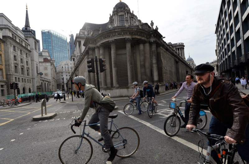 © Reuters. FILE PHOTO: Commuters cycle past the Bank of England in the City of London