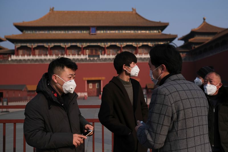 © Reuters. People wearing protective masks stand outside the main entrance of the Forbidden City where a notice is seen saying that the place is closed to visitors for the safety concern following the outbreak of a new coronavirus, in Beijing