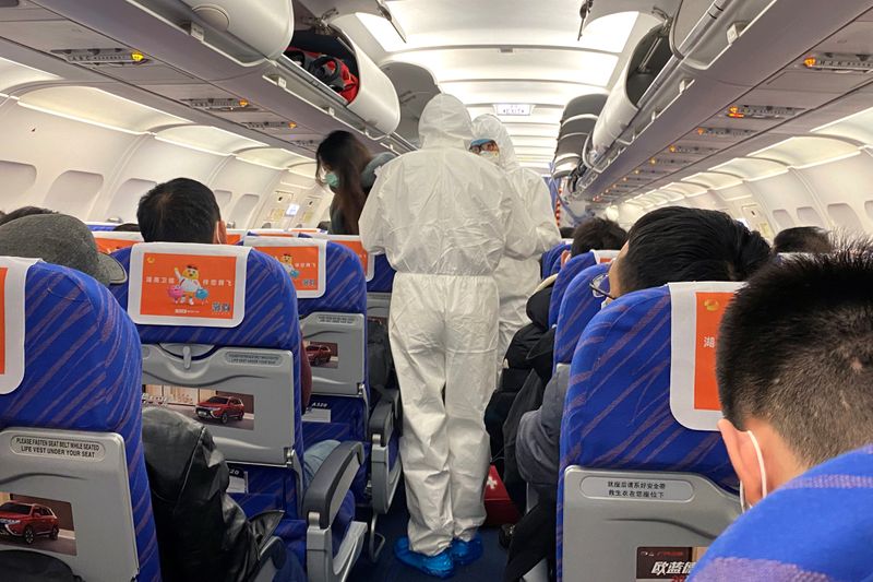 © Reuters. Trabajadores de salud con trajes protectores verifican la condición de un pasajero en un avión que acaba de aterrizar desde Changsha, una ciudad en una provincia vecina al centro del brote de coronavirus, en Shanghái, China.