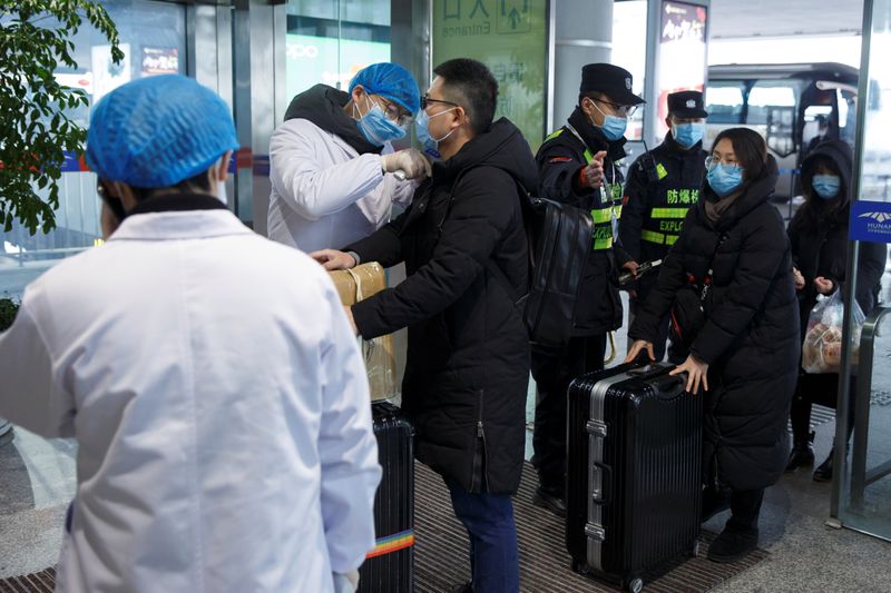 © Reuters. A medical official takes the body temperature of a man at the departure hall of the airport in Changsha