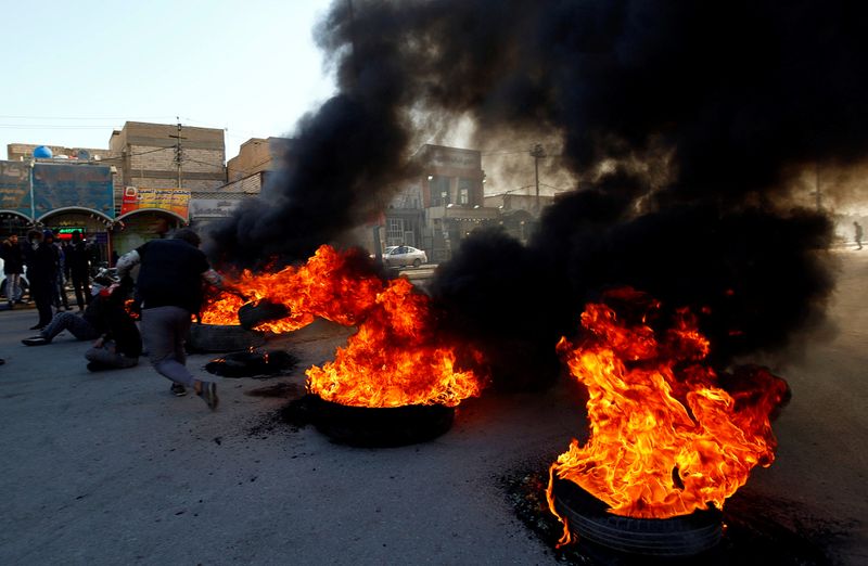 © Reuters. Iraqi demonstrators burn tires to block a road during ongoing anti-government protests in Najaf