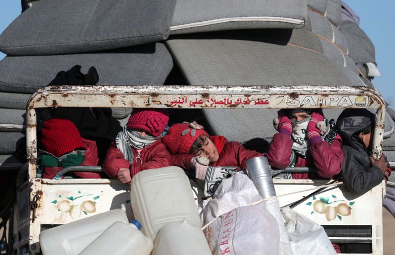 © Reuters. Displaced Syrian children ride with belongings at a back of a truck