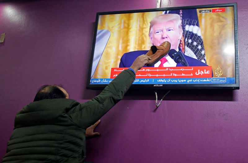 © Reuters. Foto del martes de un palestino apoyando un zapato sobre una TV en medio del discurso del presidente de EEUU, Donald Trump, sobre el anuncio de un plan de paz para Oriente Próximo