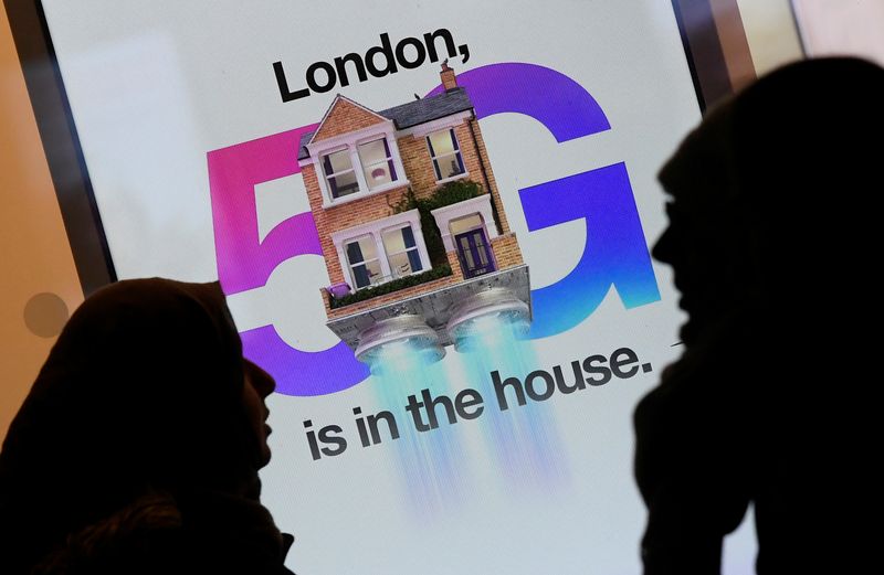 © Reuters. Pedestrians walk past an advertisement promoting the 5G data network at a mobile phone store in London