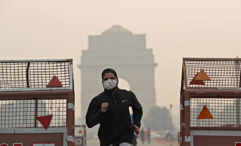 © Reuters. FILE PHOTO: A man wearing a mask runs past the India Gate on a smoggy morning in New Delhi
