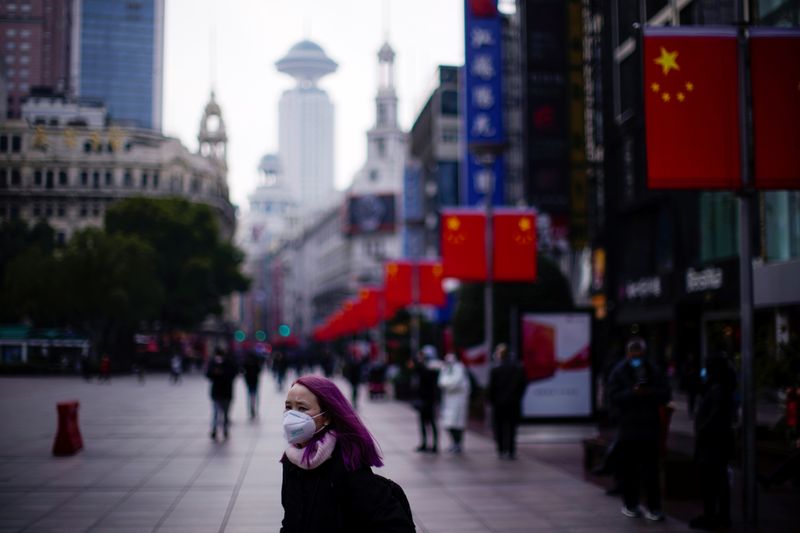 © Reuters. A woman wearing a protective mask stands at the Nanjing Road, in Shanghai