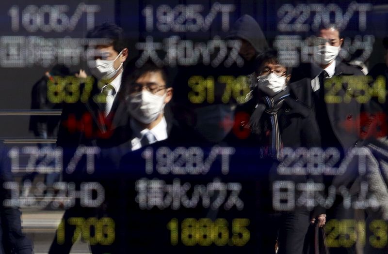 © Reuters. Pedestres utilizam máscaras em frente a painel de ações em Tóquio