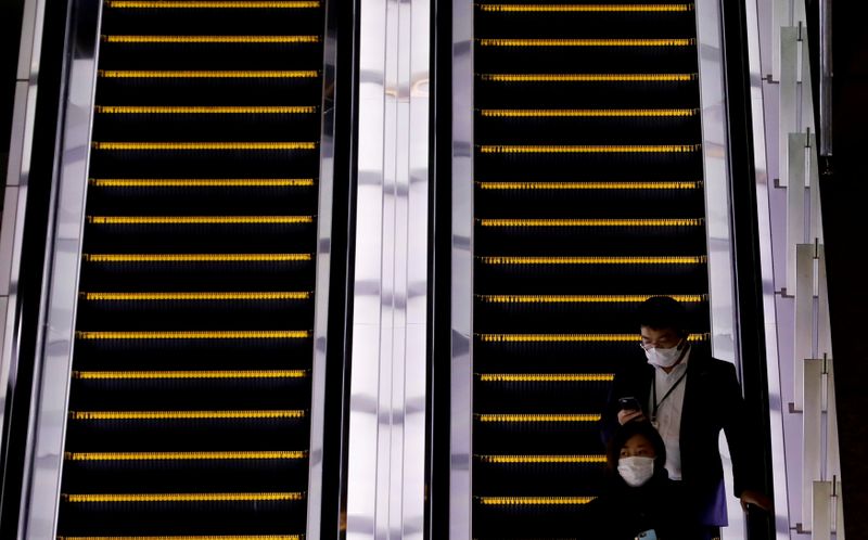 © Reuters. Pedestres usam máscara de proteção em escada rolante de bairro empresarial de Tóquio