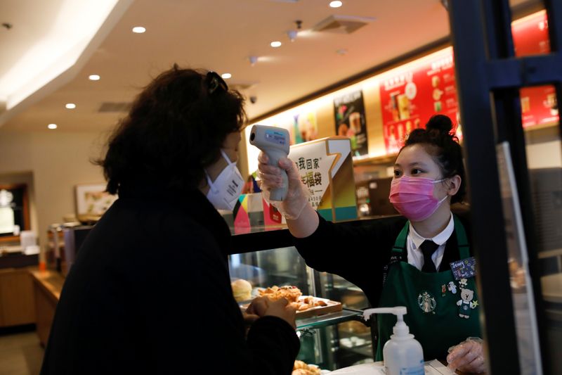 © Reuters. Una trabajadora toma la temperatura de un cliente en una tienda de Starbucks en Pekín.