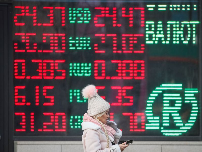 © Reuters. Una mujer pasa junto a una pizarra que muestra los tipos de cambio en el centro de Kiev