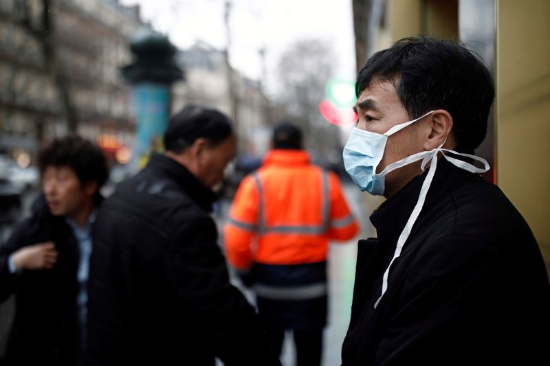 © Reuters. Tourist wears a protective mask in front of the Galeries Lafayette department store in Paris as the country is hit by the new coronavirus