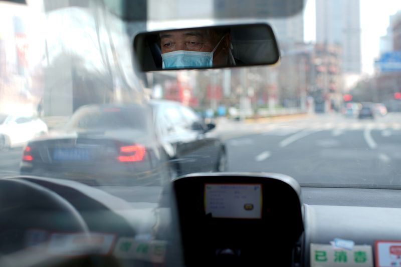 © Reuters. FILE PHOTO: A taxi driver wears a mask as he drives on a street in Shanghai