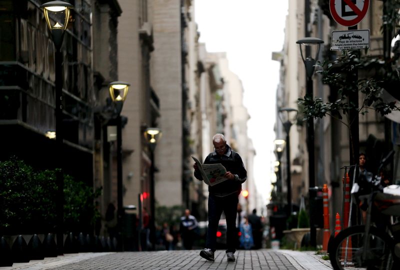 © Reuters. A man reads a newspaper as he walks in Buenos Aires' financial district