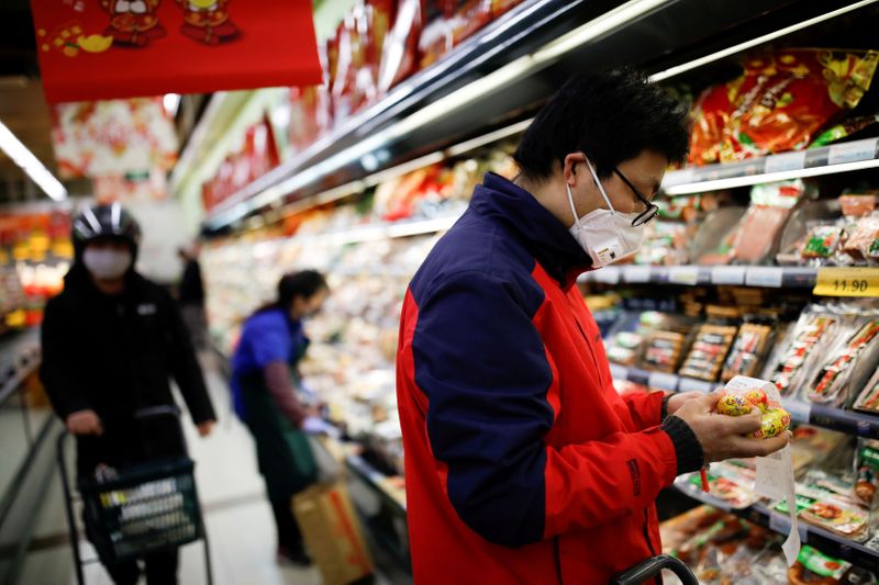 © Reuters. Las personas que usan mascarillas buscan productos en un supermercado, cuando China se ve afectada por un brote de un nuevo coronavirus, en Pekín.