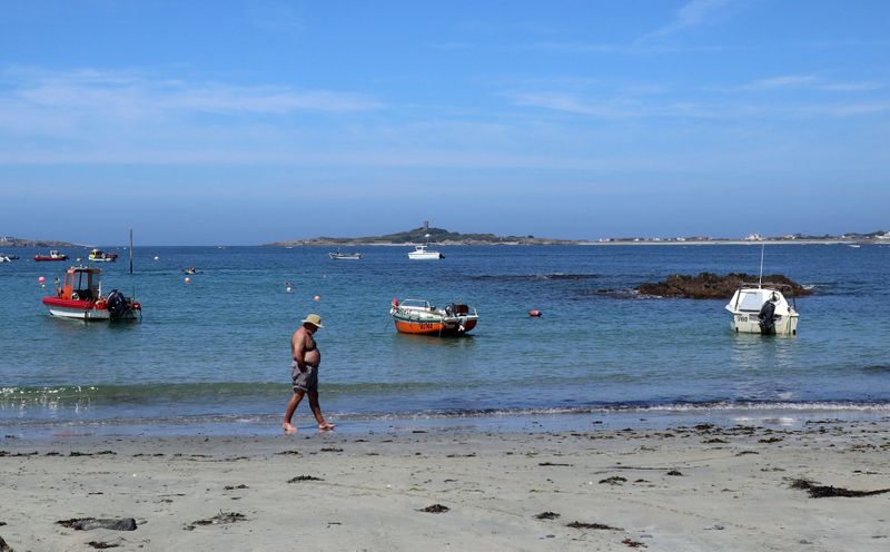 © Reuters. A man walks along the beach in Guernsey, one of the Channel Islands