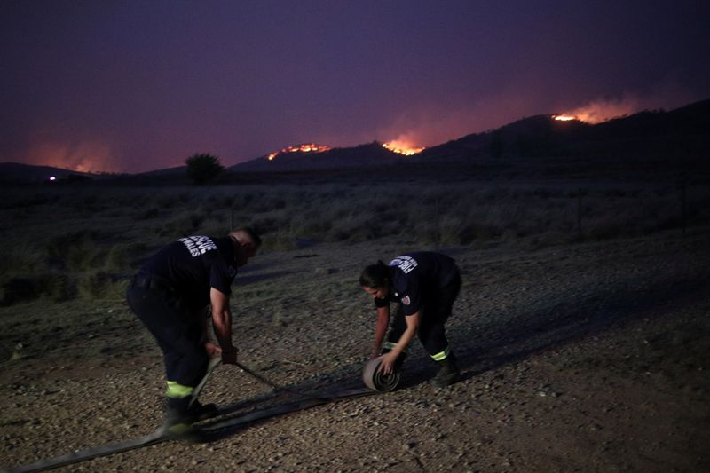 © Reuters. Personnel from Fire and Rescue NSW work as a bushfire approaches a home in Bredbo