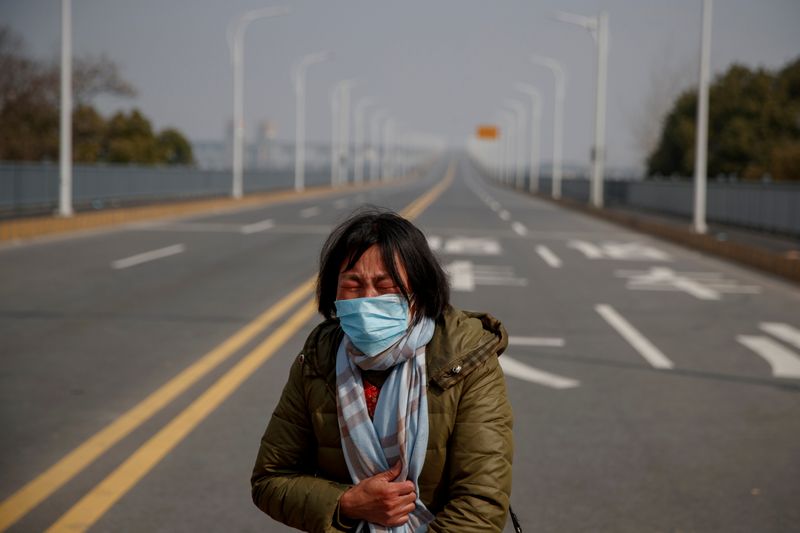 © Reuters. A mother reacts as she pleads with police to allow her daughter to pass a checkpoint for cancer treatment after she arrived from Hubei province at the Jiujiang Yangtze River Bridge in Jiujiang