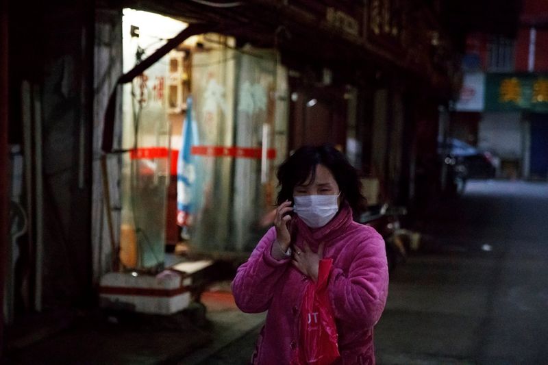 © Reuters. Woman wears a face mask in a market alley in Jiujiang