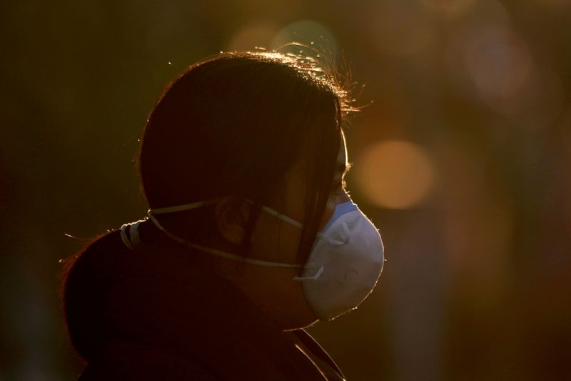 © Reuters. A woman wearing a mask is seen on a street in Shanghai, China, as the country is hit by an outbreak of a new coronavirus