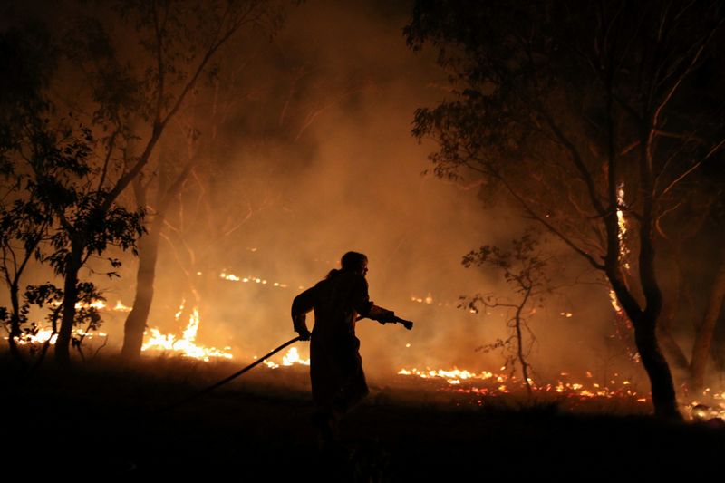 © Reuters. A firefighter works to extinguish flames after a bushfire burnt through the area in Bredbo