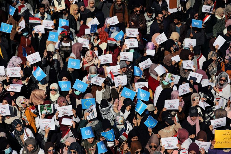 © Reuters. University students carry posters depicting the newly appointed Prime Minister of Iraq, Mohammed Tawfiq Allawi, to express their rejection of him, during ongoing anti-government protests in Kerbala