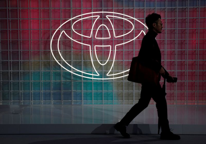 © Reuters. FILE PHOTO:  A man walks past a Toyota logo at the Tokyo Motor Show