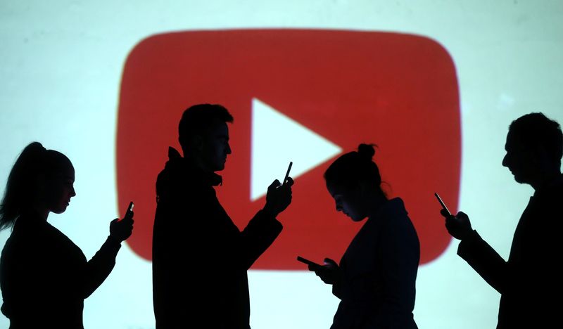 © Reuters. Silhouettes of mobile users are seen next to a screen projection of Youtube logo in this picture illustration