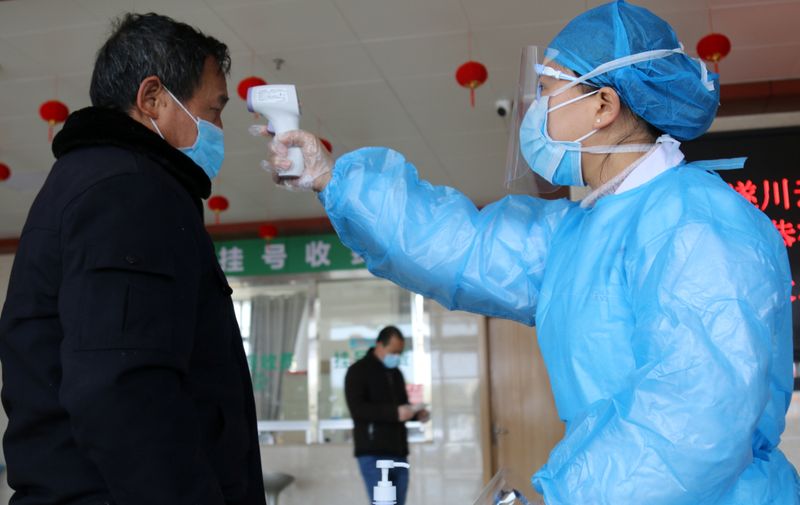 © Reuters. Medical worker takes body temperature measurement of a man at an entrance to a hospital as the country is hit by an outbreak of the new coronavirus, in Suichuan