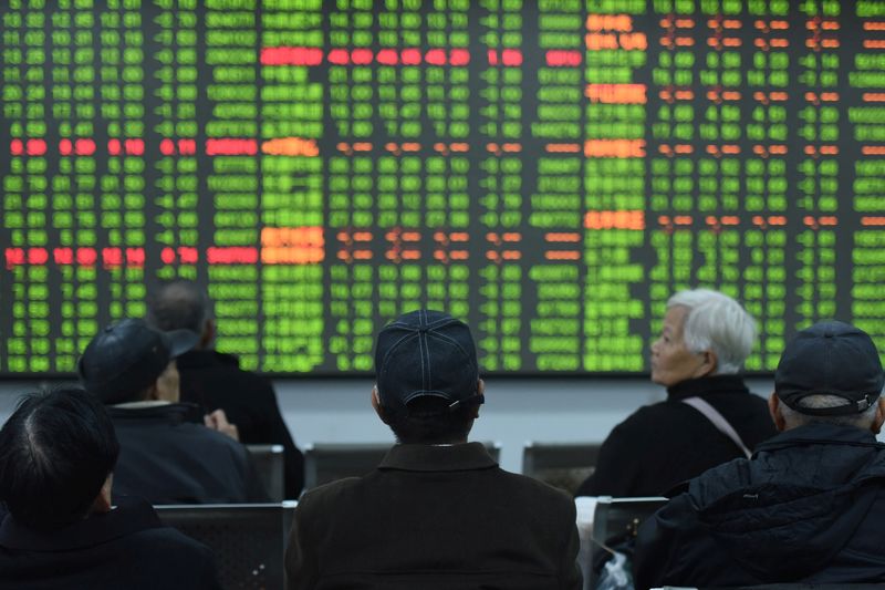 © Reuters. Investors sit in front of a board showing stock information at a brokerage house on the first day of trade in China since the Lunar New Year, in Hangzhou