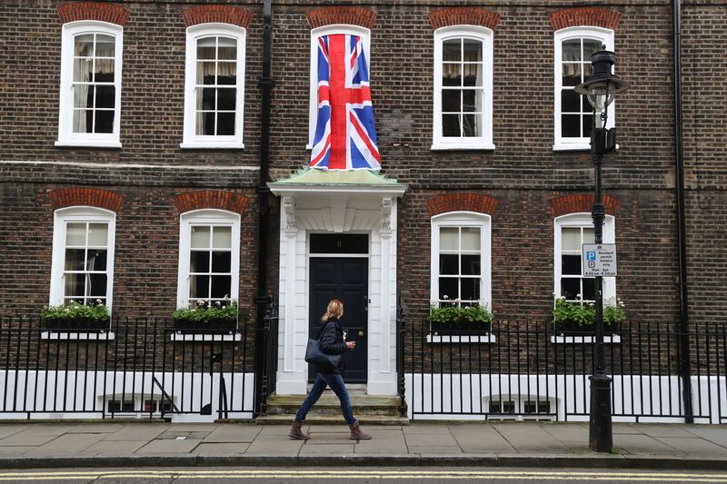 © Reuters. Woman walks past a Union Jack flag hanging on a house in Westminster in London