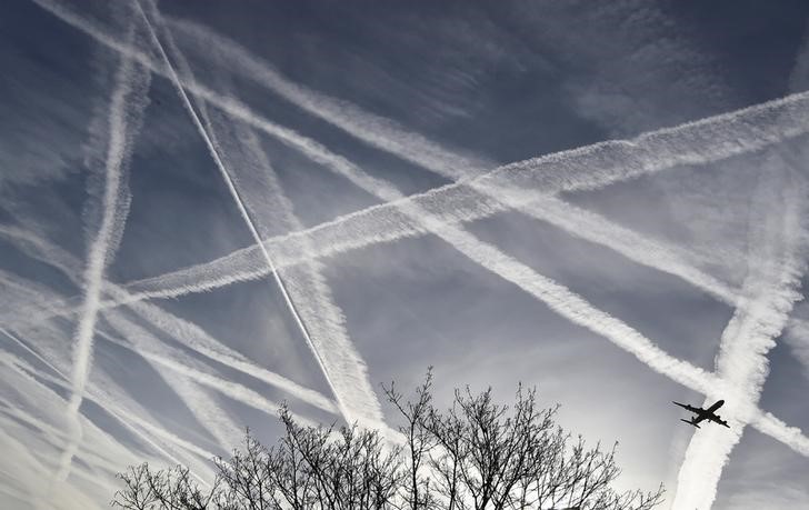 © Reuters. A passenger plane flies through aircraft contrails in the skies near Heathrow Airport in west London