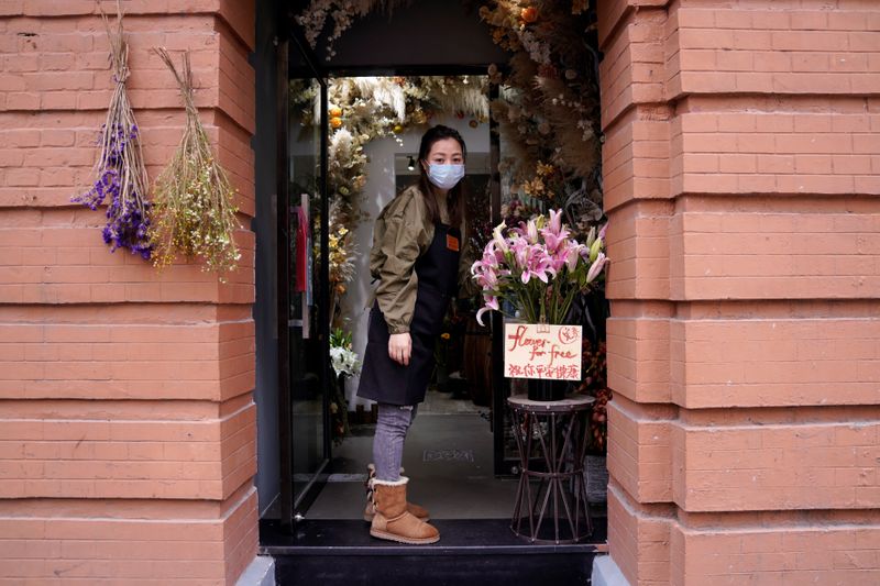 © Reuters. Florist Wang Haiyan, 41, stands at an entrance to her shop as the country is hit by an outbreak of the new coronavirus, in Shanghai