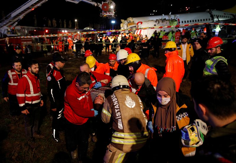 © Reuters. An injured person is carried away from Pegasus Airlines Boeing 737-86J plane, after it overran the runway during landing and crashed, at Istanbul's Sabiha Gokcen airport